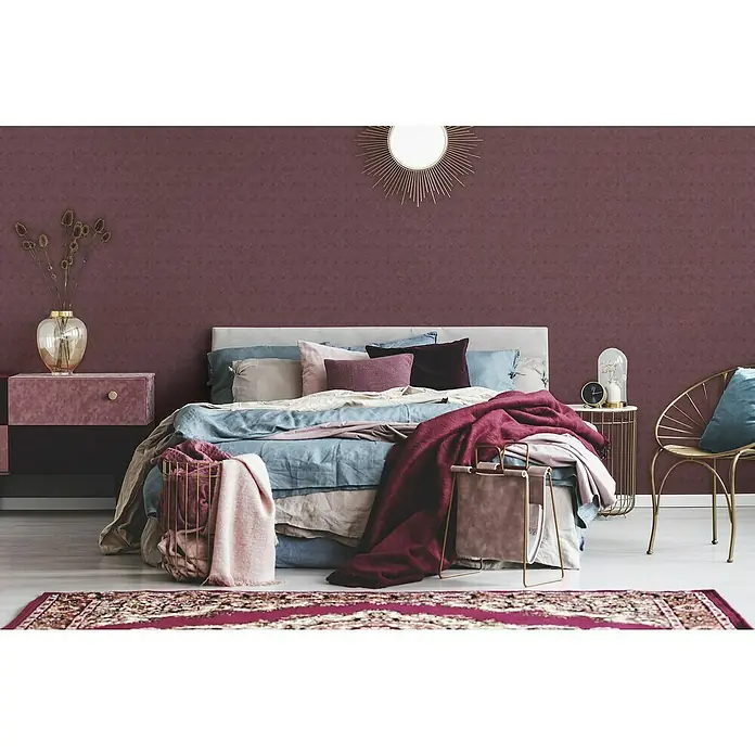 A.S. Création Cuba Vliestapete Design - Rot, Grafisch, 10,05 x 0,53 m - Ein Schlafzimmer mit einem großen Bett, einem Nachttisch und einem Sessel. Die Wand ist in einem dunklen Rotton gehalten.