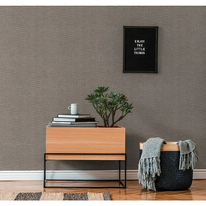 A.S. Création Hygge 2 Vliestapete Geometrie - Grau, Grafisch, 10,05 x 0,53 m - Nahaufnahme eines stilvollen Wohnzimmers mit einem Holzschrank, Topfpflanze, einer schwarzen Filztafel und einem Korb mit einer grauen Decke.