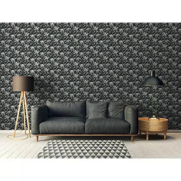 A.S. Création Michalsky 4 Vliestapete Allover mit Affen - Schwarz/Grau, Tieroptik, 10,05 x 0,53 m - Dunkle Tapete mit einem Muster aus hellen Affen und Ranken, an einer Wohnzimmerwand hinter einem grauen Sofa.