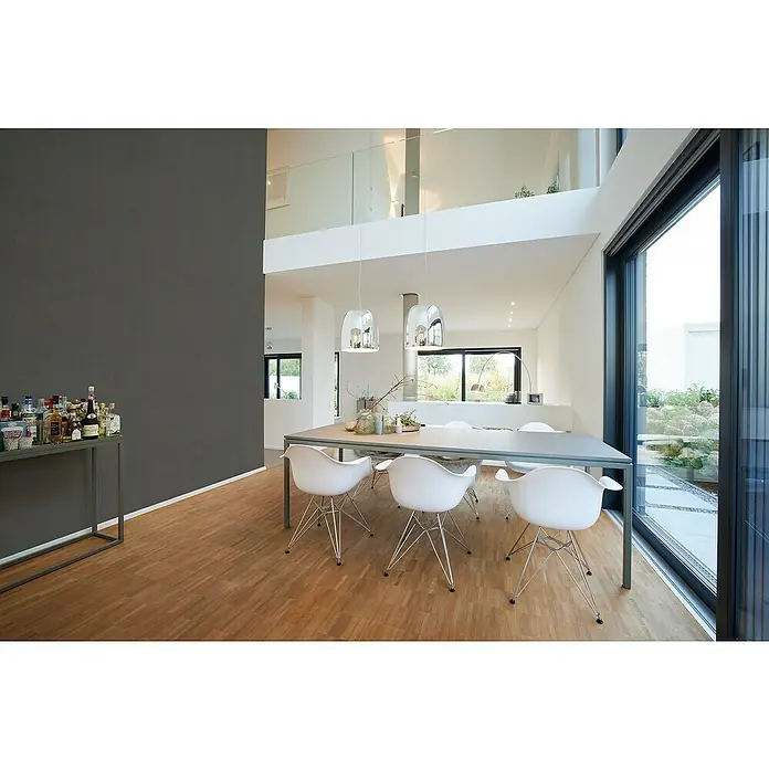 A.S. Création My Home My Spa Vliestapete - Anthrazit Metallic, Uni, 10,05 x 0,53 m - Esszimmer mit modernem Esstisch und stilvollen Stühlen, beleuchtet von eleganten Hängelampen. Große Fenster bieten einen Blick ins Grüne.