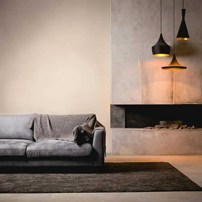 A.S. Création My Home My Spa Vliestapete Textstruktur I - Weiß/Grau, Uni, 10,05 x 0,53 m - Moderne Wohnzimmeransicht mit grauem Sofa, Teppich und minimalistischen Pendelleuchten über einem dekorativen Kamin. Elegantes Design für Wohnraum.