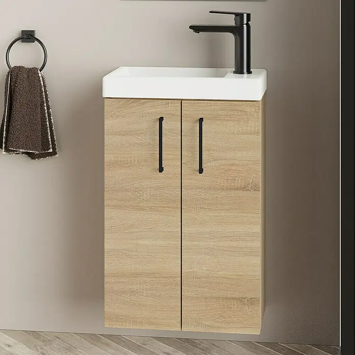 Artysan Conjunto de mueble de baño Super Mini - Natural, 3 pzs. - Mueble de lavabo de madera clara con encimera blanca y grifo negro, junto con un toallero de aro con una toalla.
