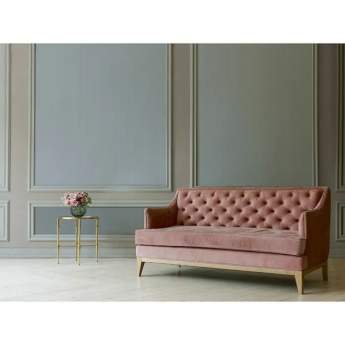 A.S. Création Mata Hari Vliestapete - Grau, Uni, 10,05 x 0,53 m - Ein elegantes, altrosa Samtsofa mit Knopfheftung steht vor einer stilvollen Wand. Der sanfte Farbton des Sofas ergänzt die gedämpfte Farbpalette des Raumes.