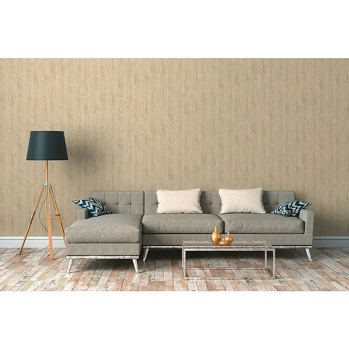 A.S. Création Hygge 2 Vliestapete Bäume - Beige, Floral, 10,05 x 0,53 m - Zimmeransicht mit grauer Couch, Kissen, Lampe und Tisch. Die Couch ist das zentrale Element des Raumes.