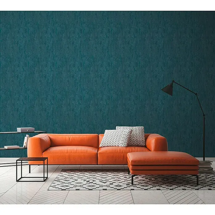A.S. Création Trendwall 2 Vliestapete Rostoptik - Rost/Blau, Metalloptik, 10,05 x 0,53 m - Modernes Wohnzimmer mit einem orangefarbenen Ledersofa, einem passenden Ottomanen und einem geometrischen Teppich. Elegante Beleuchtung und minimalistische Regale.