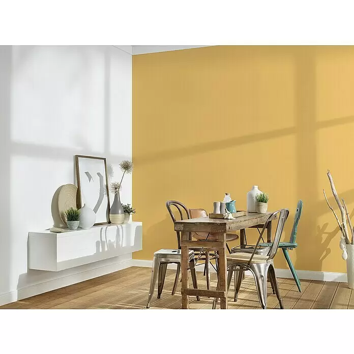A.S. Création Michalsky 4 Vliestapete - Gelb, Uni, 10,05 x 0,53 m - Ein heller Essbereich mit rustikalem Holztisch, verschiedenen Stühlen und einem weißen Wandregal vor einer zweifarbigen Wand.