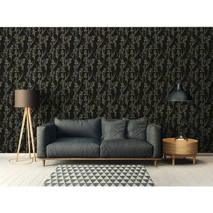 A.S. Création Daniel Hechter 6 Vliestapete Blumen - Schwarz/Braun, Floral, 10,05 x 0,53 m - Gemütliches Wohnzimmer mit stilvollem Sofa, Stehleuchte und Beistelltisch vor einer floralen Tapete, die eine warme und einladende Atmosphäre schafft.