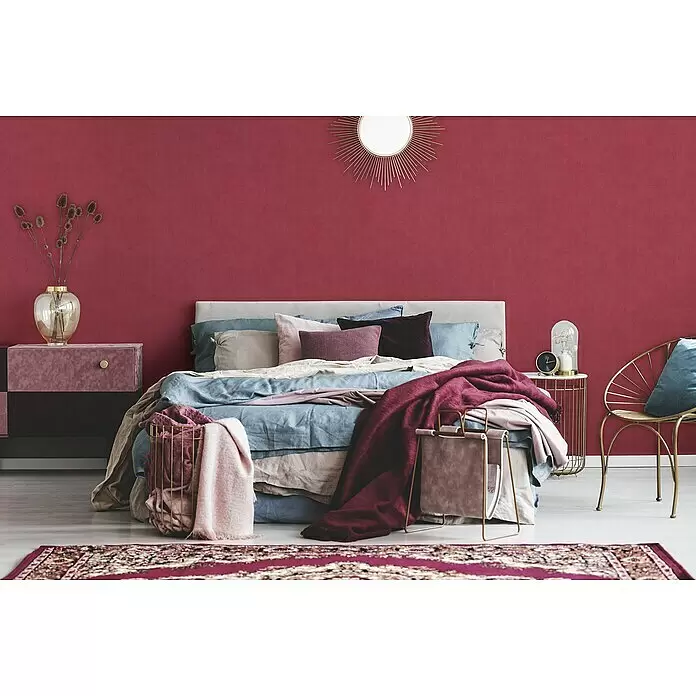 A.S. Création Cuba Vliestapete - Rot, Uni, 10,05 x 0,53 m - Schlafzimmer mit tiefroter Strukturwand und einem Bett mit kühl getönter Leinenbettwäsche.