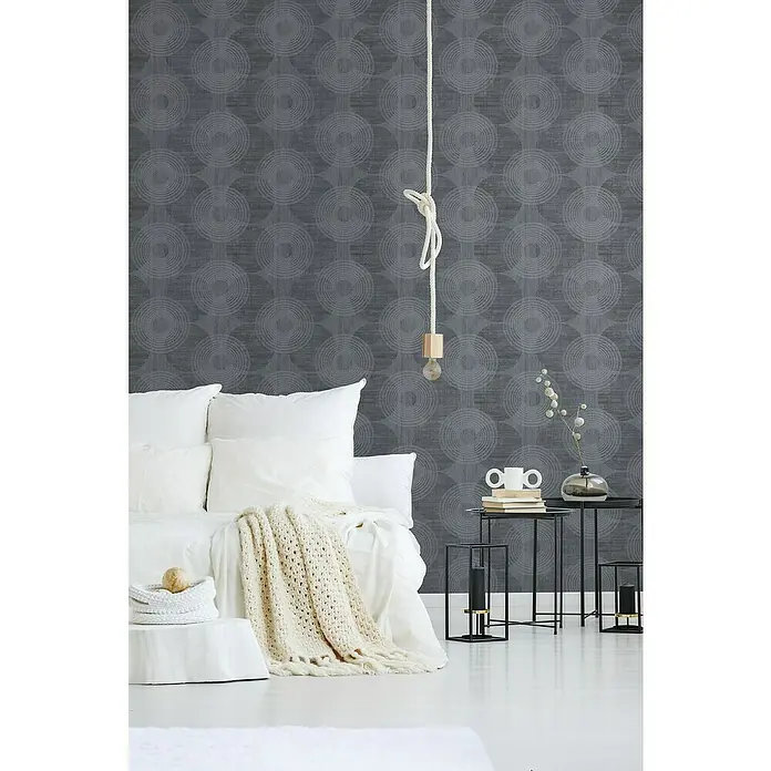 A.S. Création Attractive Vliestapete Große Kreise - Grau-Schwarz, Grafisch, 10,05 x 0,53 m - Ein Schlafzimmer mit einem Nachttisch und einer hängenden Glühbirne vor einer gemusterten Wand.