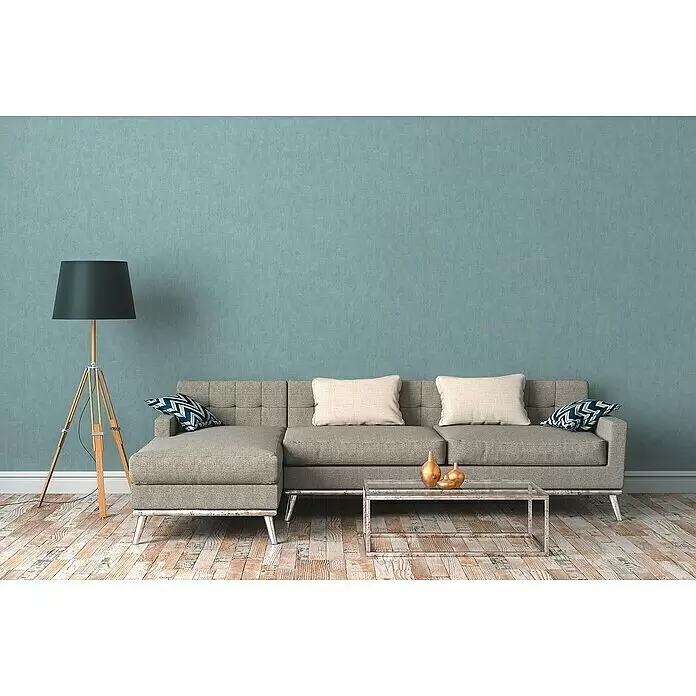 A.S. Création Cuba Vliestapete - Blau, Uni, 10,05 x 0,53 m - Ein bequemes graues Ecksofa aus Stoff mit Zierkissen in einem modernen Wohnzimmer.