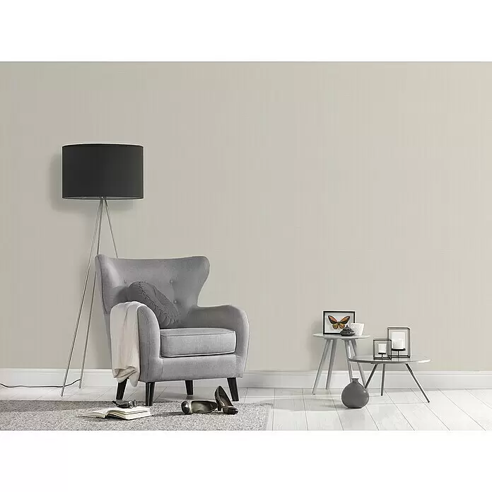 A.S. Création Desert Lodge Vliestapete - Kieselgrau hell, Uni, 10,05 x 0,53 m - Hellbeige strukturierte Tapete an einer Wand im Wohnzimmer, bildet einen neutralen Hintergrund für Möbel.