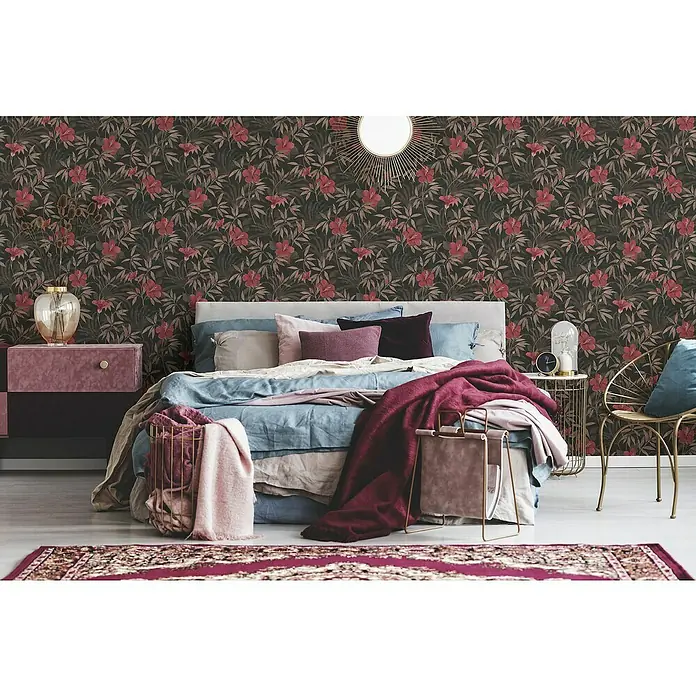 A.S. Création Cuba Vliestapete Blume - Rot/Braun, Floral, 10,05 x 0,53 m - Schlafzimmer mit einem floral gemusterten Wandbild in dunklen Farben, Bett mit vielen Kissen und Tagesdecke.