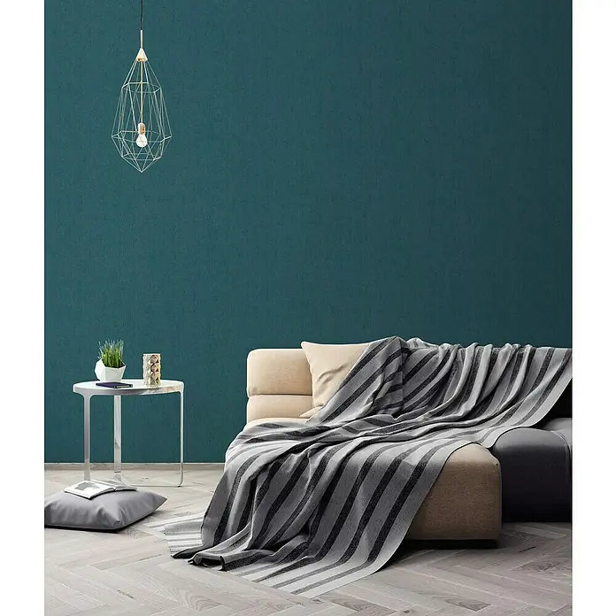 A.S. Création Titanium 3 Vliestapete - Maritimes Blau, Uni, 10,05 x 0,53 m - Nahaufnahme eines modernen Wohnzimmers mit grau gestreifter Decke über einem beigen Sofa, Lampe und Beistelltisch.