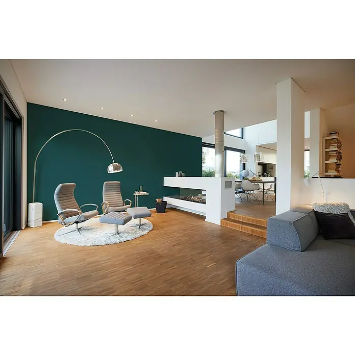 A.S. Création My Home My Spa Vliestapete Textstruktur I - Petrol, Uni, 10,05 x 0,53 m - Innenaufnahme eines Wohnraums mit grauen Sesseln, einem Kamin und einer grauen Couch. Helle Holzböden und Akzentwand in dunklem Grün.