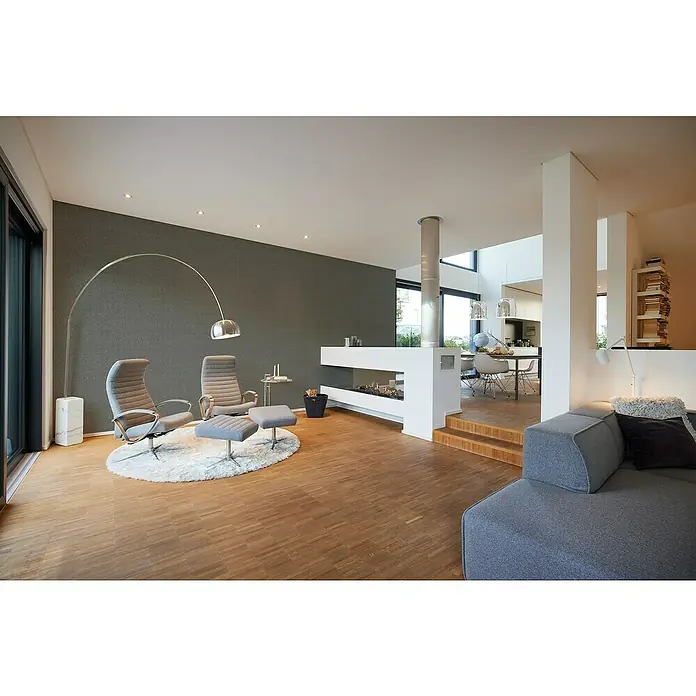 A.S. Création My Home My Spa Vliestapete - Metallisches Anthrazit, Uni, 10,05 x 0,53 m - Ein helles, modernes Wohnzimmer mit grauem Sofa, Sesseln und einem stilvollen Kamin. Der Raum wirkt einladend und minimalistisch.