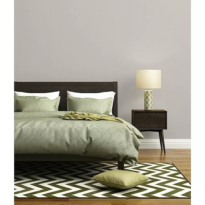 A.S. Création Trendwall 2 Vliestapete - Grau, Uni, 10,05 x 0,53 m - Gemusterte Bettwäsche in Salbeigrün und ein Chevron-Teppich schmücken ein dunkelbraunes Bett in einem modernen Schlafzimmer.