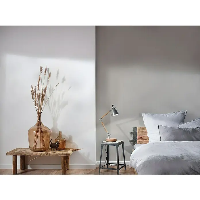 A.S. Création Mata Hari Vliestapete - Beige, Uni, 10,05 x 0,53 m - Zimmer mit großem Glasballon auf Holztisch, Lampe auf kleinem Tisch, rustikalem Bett und Kissen für ein gemütliches Ambiente.