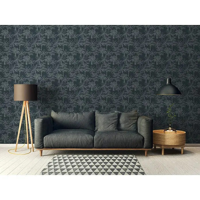 A.S. Création Michalsky 4 Vliestapete Palmen - Schwarz/Grau, Floral, 10,05 x 0,53 m - Wohnzimmer-Szene mit einem grauen Sofa, einem dreibeinigen Stehlampe und einem runden Beistelltisch mit einer Lampe, die eine gemütliche Atmosphäre schaffen.