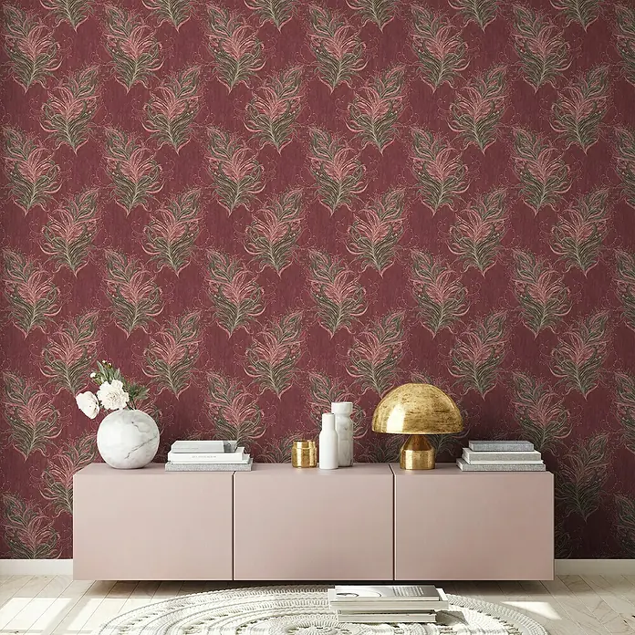 A.S. Création Mata Hari Vliestapete Federn - Rot/Braun, Tieroptik, 10,05 x 0,53 m - Nahaufnahme eines Raumes mit einer Kommode in Rosa, einer Lampe und Dekoration vor einer Wand mit Federmuster Tapete.
