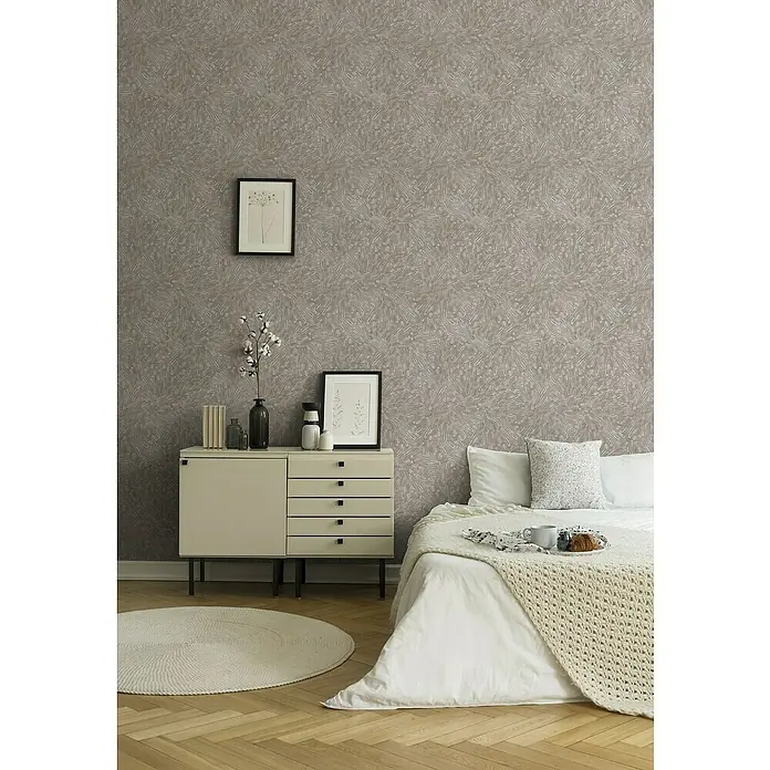 A.S. Création Titanium 3 Vliestapete Dynamischer 3D-EffektBeige, 3D-Optik, 10,05 x 0,53 m - Helles Schlafzimmer mit einem Nachttisch, auf dem Vasen und Bücher stehen, sowie einem Bett mit weißer Bettwäsche und einer Strickdecke.