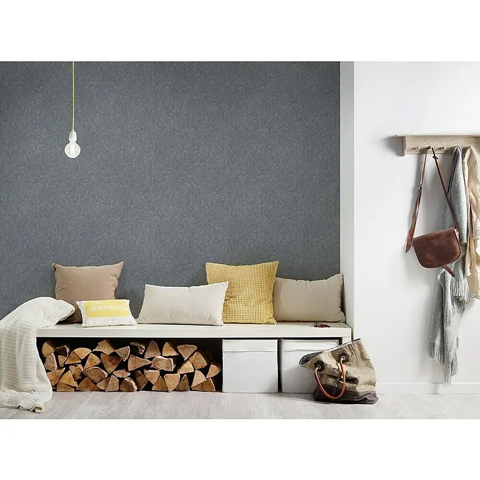 A.S. Création Titanium 3 Vliestapete Dynamischer 3D-Effekt - Grau, 3D-Optik, 10,05 x 0,53 m - Stimmungsvolles Interieur mit grauer Tapete, Kissen und Holzlager unter einer Sitzbank. Ein schöner, einladender Raum mit Textilien.