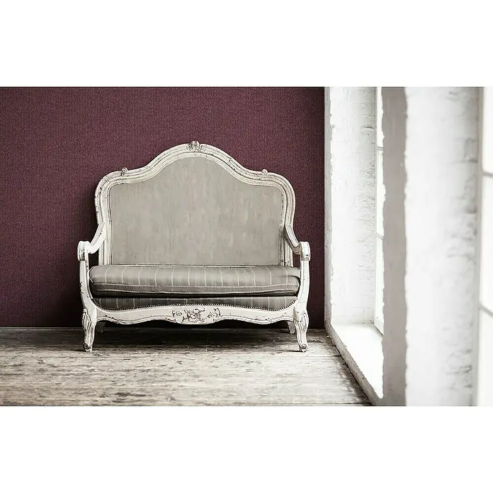 A.S. Création Mata Hari Vliestapete Kleinmuster - Rot, Uni, 10,05 x 0,53 m - Antikes Sofa mit weißem Rahmen und gestreiftem Sitzkissen vor einer weinroten Wand und einem hellen Fenster.
