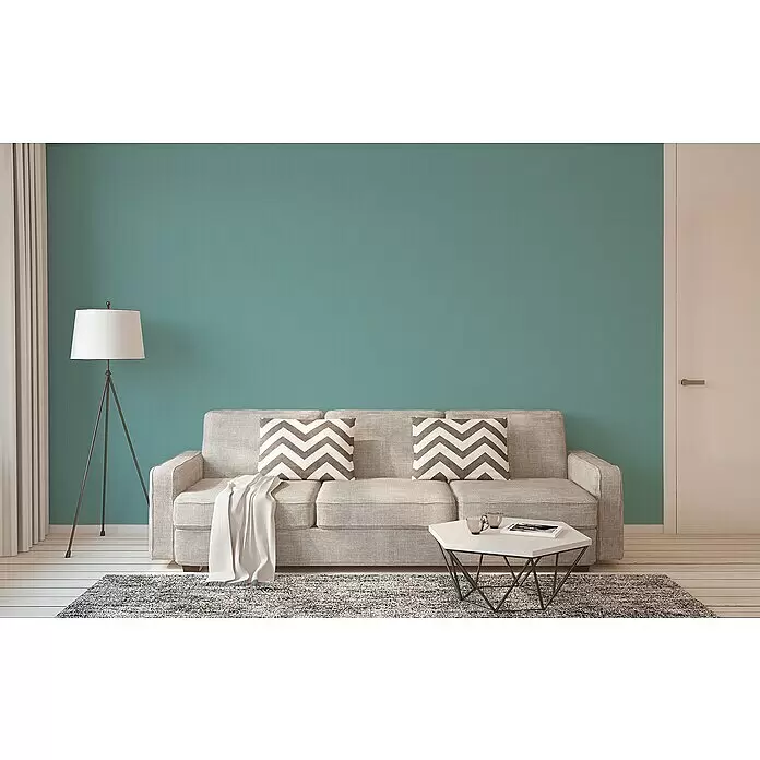 A.S. Création Trendwall 2 Vliestapete - Blau, Uni, 10,05 x 0,53 m - Helles graues strukturiertes Sofa mit gemusterten Kissen und einer weißen Decke im modernen Wohnzimmer.
