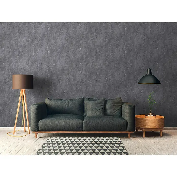 A.S. Création Titanium 3 Vliestapete I - Anthrazit, Betonoptik, 10,05 x 0,53 m - Elegantes Wohnzimmer mit einem grauen Sofa, einer Stehlampe und einem runden Beistelltisch unter einer modernen Hängelampe.