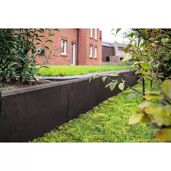 Diephaus L-Stein - 50 cm, 50 cm, Stärke: 7 cm, Anthrazit - Dunkelgraue Beton-Gartenkante trennt ein Blumenbeet mit Pflanzen von einem grünen Rasen.