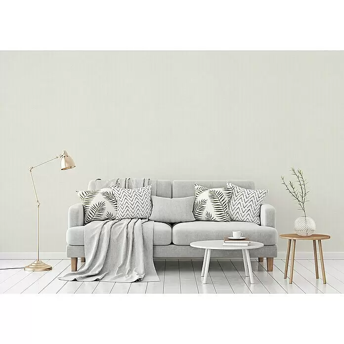 A.S. Création Titanium 3 Vliestapete - Pastellweiß, Uni, 10,05 x 0,53 m - Ein hellgraues Sofa mit gemusterten Kissen und einer Decke in einem minimalistischen Wohnzimmer.