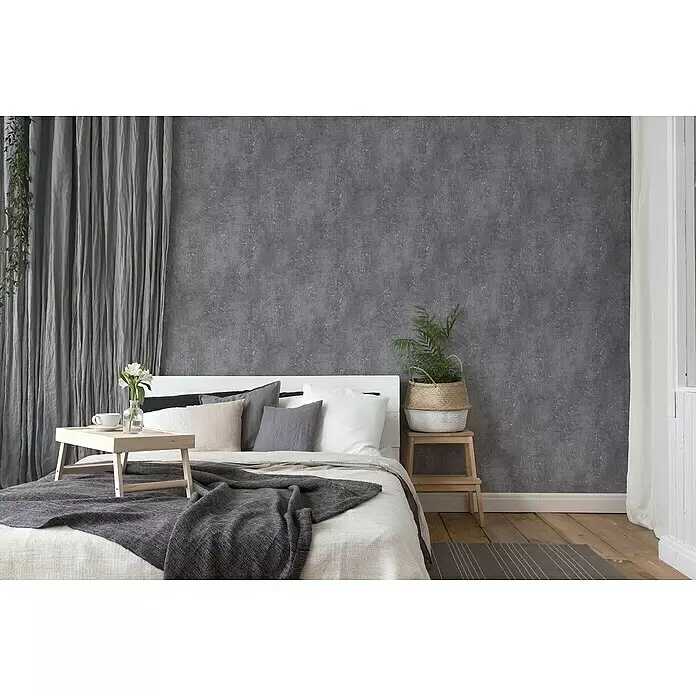 A.S. Création Titanium 3 Vliestapete I - Anthrazit, Betonoptik, 10,05 x 0,53 m - Dunkelgraue strukturierte Tapete in einem modernen Schlafzimmer.