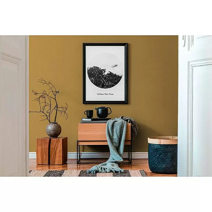 A.S. Création Hygge 2 Vliestapete Gewebe - Gelb/Gold, Uni, 10,05 x 0,53 m - Modernes Interieur mit senfgelber Wand, gerahmtem Bergdruck, Holzmöbeln und Deko.