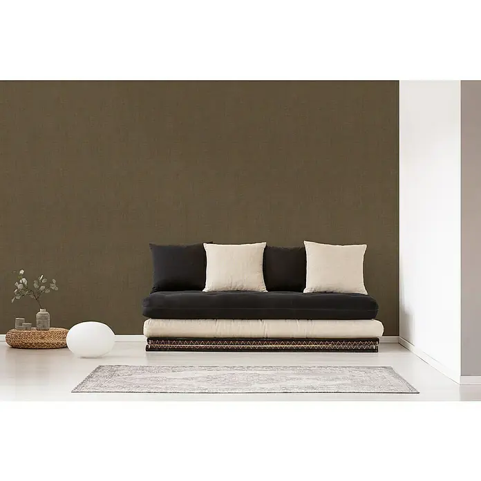 A.S. Création Cuba VliestapeteBraun, Streifen, 10,05 x 0,53 m - Einrichtungsszene mit einem bequemen Futonbett mit Kissen, das zum Entspannen einlädt, und einem stilvollen Teppich in einem modernen Raum.
