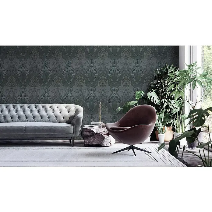 A.S. Création My Home My Spa Vliestapete Damask Paisley - Schwarz, Ornament, 10,05 x 0,53 m - Wohnzimmer mit grauem Sofa, braunem Sessel und vielen Zimmerpflanzen. Wand mit dunklem Tapetenmuster.