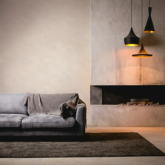A.S. Création My Home My Spa Vliestapete Marmor - Weiß, Steinoptik, 10,05 x 0,53 m - Elegantes Wohnzimmer mit grauem Sofa, gemütlicher Decke, modernem Kamin und drei stilvollen Hängelampen, die warmes Licht spenden.