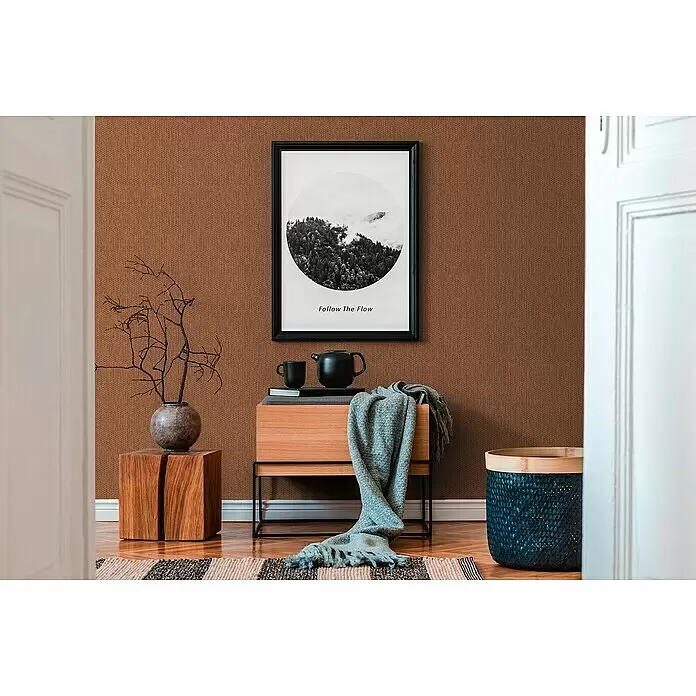A.S. Création Hygge 2 Vliestapete Bambusstruktur - Rot/Braun, Uni, 10,05 x 0,53 m - Strukturierte braune Tapete mit feinem Webmuster an einer Wand.