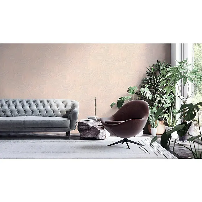 A.S. Création My Home My Spa Vliestapete Kreisdesign - Rosè, Grafisch, 10,05 x 0,53 m - Stilvolles Interieur mit grauem Sofa, braunem Sessel, Steintisch und Zimmerpflanzen vor einer Wand mit Kreisornamenten.