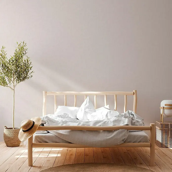 A.S. Création Titanium 3 Vliestapete - Helles Weißbeige, Uni, 10,05 x 0,53 m - Helles Schlafzimmer mit einem schlichten Holzbett, weißen Laken und Kissen. Eine Zimmerpflanze und ein Strohhut sorgen für ein gemütliches Ambiente.