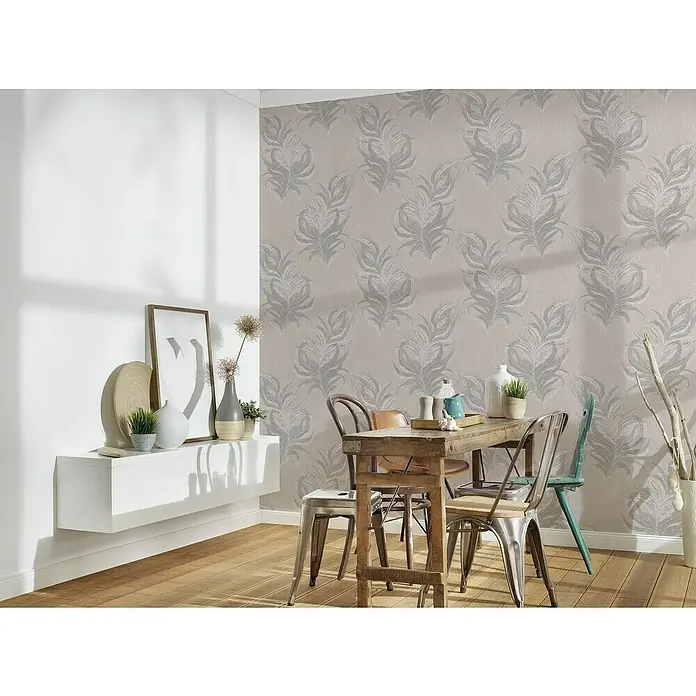 A.S. Création Mata Hari Vliestapete Federn - Beige/Grau, Tieroptik, 10,05 x 0,53 m - Ein Esstisch mit Metallstühlen steht vor einer Wand mit Feder-Tapete. Auf dem Tisch stehen Deko-Elemente und Geschirr für eine einladende Atmosphäre.