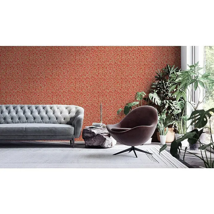 A.S. Création My Home My Spa Vliestapete Tetris - Rot Metallic, Grafisch, 10,05 x 0,53 m - Wohnzimmer mit roter Mustertapete, grauer Couch, Sessel und Pflanzen. Die Tapete mit abstraktem Design prägt den Raum und sorgt für eine warme Atmosphäre.
