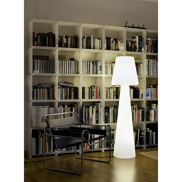 New Garden Lámpara de diseño para exterior LED Lola - 8 W, Blanco frío, Altura: 165 cm - Una lámpara de pie iluminada con una pantalla blanca, situada junto a una silla de cuero negro frente a una estantería.