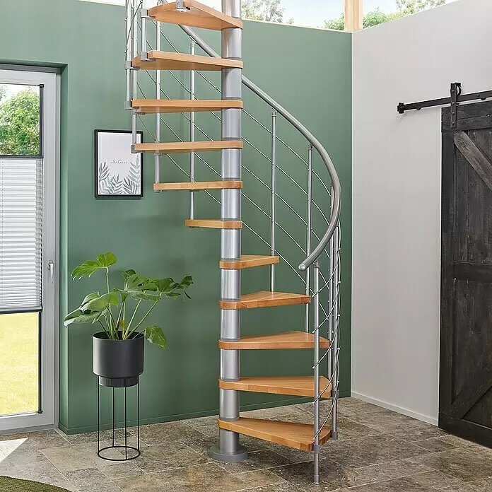 Dolle Spindeltreppe Oslo - Durchmesser: 120 cm, Grau, Farbe Stufen: Buche Natur, Geschosshöhe: 294 cm - 322 cm - Wendeltreppe mit hellen Holzstufen und einer silbernen Metallsäule sowie Geländer, die in einem Raum nach oben führt.