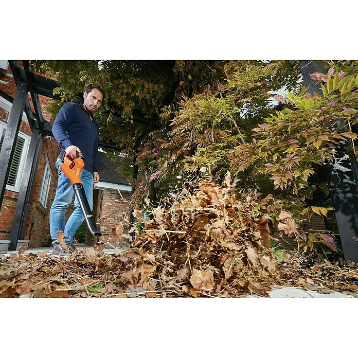 Black+Decker Soplador de hojas de batería Boost - 18 V, 2 Ah, Velocidad de soplado: 209 km/h, Potencia de soplado: 1,5 m³/min - Un hombre usa un soplador de hojas para limpiar las hojas de un patio. El soplador de hojas Black+Decker es una herramienta útil para jardinería.