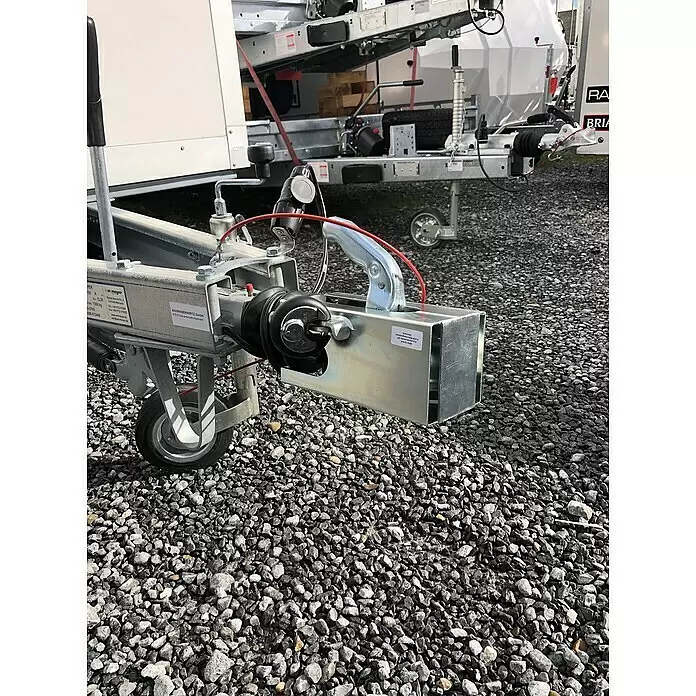 Basi Diebstahlsicherung KFZ 114 - Aluminium, Verzinkt - Galvanisierte Anhängerkupplung und Chassisbaugruppe mit schwarzem Faltenbalg und rotem Kabel auf Schotter.