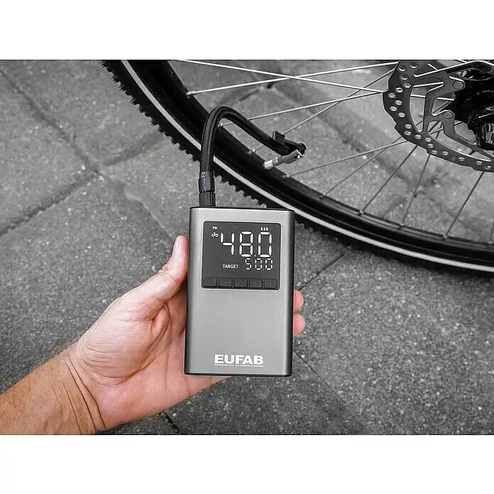 Eufab Kompressor - 12 V - Graue tragbare Luftpumpe in der Hand, angeschlossen an einen Fahrradreifen und 48,0 PSI anzeigend.