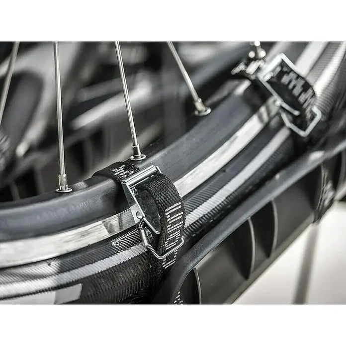 Eufab Spanngurt - 4 Stk. - Detailaufnahme eines Fahrradreifens mit Felge, Speichen und einem Gurt mit Metallschnalle zur Befestigung am Fahrradträger.