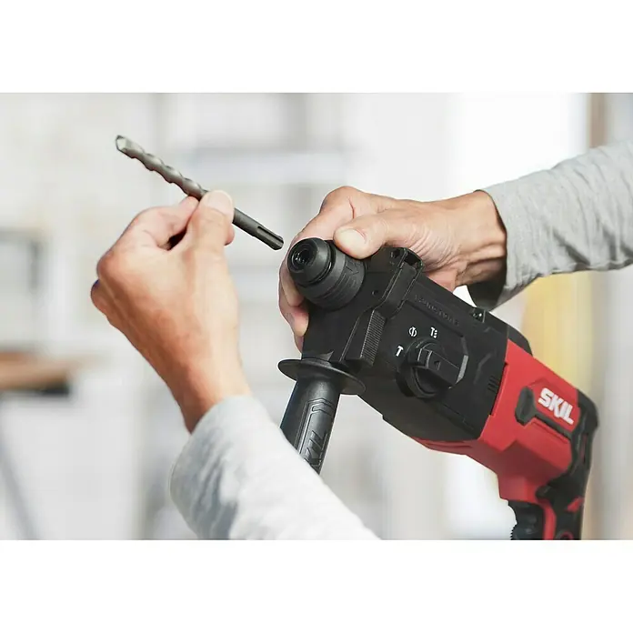 Skil Kombihammer 1770 GA - 850 W, 2,8 J, SDS-Plus-Aufnahme - Eine Nahaufnahme einer roten SKIL-Bohrmaschine, die bereit ist, mit einem Bohrer verwendet zu werden, der in der Hand gehalten wird.