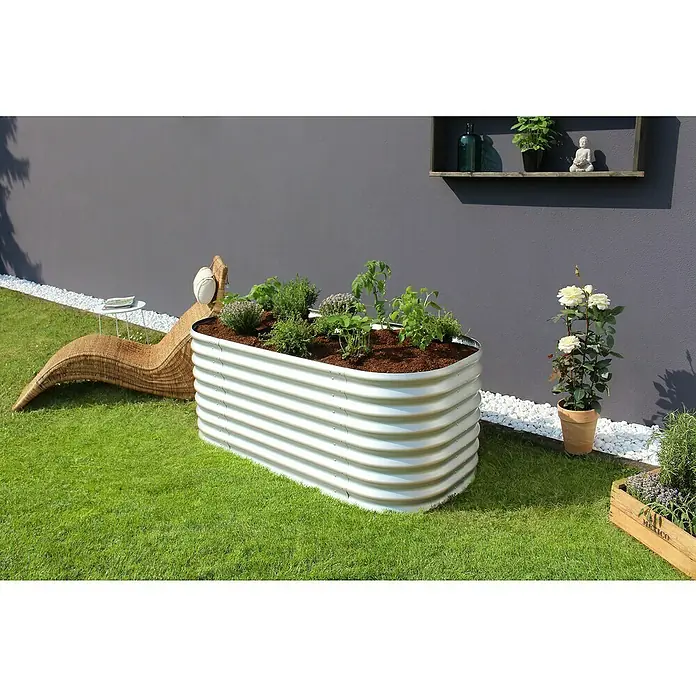 Vitavia Hochbeet Terra 630 - 162 x 82 x 63 cm, Zincalume®, Blank - Metall-Hochbeet mit Kräutern und Pflanzen auf einem Rasen mit Liegestuhl und weißen Steinen.