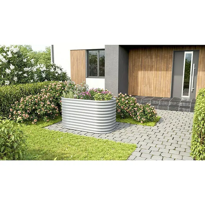 Vitavia Hochbeet Terra 858 - 162 x 82 x 85,8 cm, Zincalume®, Blank - Ein erhöhter, grauer Pflanzkasten aus Metall, der mit Blumen bepflanzt ist, steht im Vorgarten eines Hauses, umgeben von üppigem Grün.