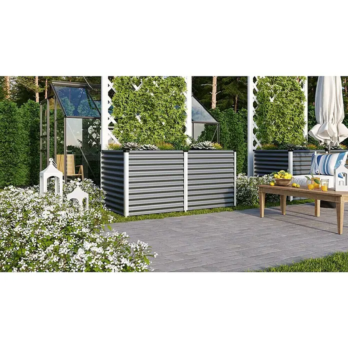 Vitavia Hochbeet Meta 858 - 187,7 x 96,2 x 85,8 cm, Zincalume®, Granit/Silber - Ein Gartenbild mit Hochbeeten aus grauem Metall, bepflanzt mit grünen Pflanzen, und einem Tisch mit Getränken auf einer gepflasterten Terrasse.